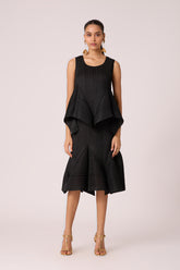 Woman wearing a black pleated skirt and a matching layered top.